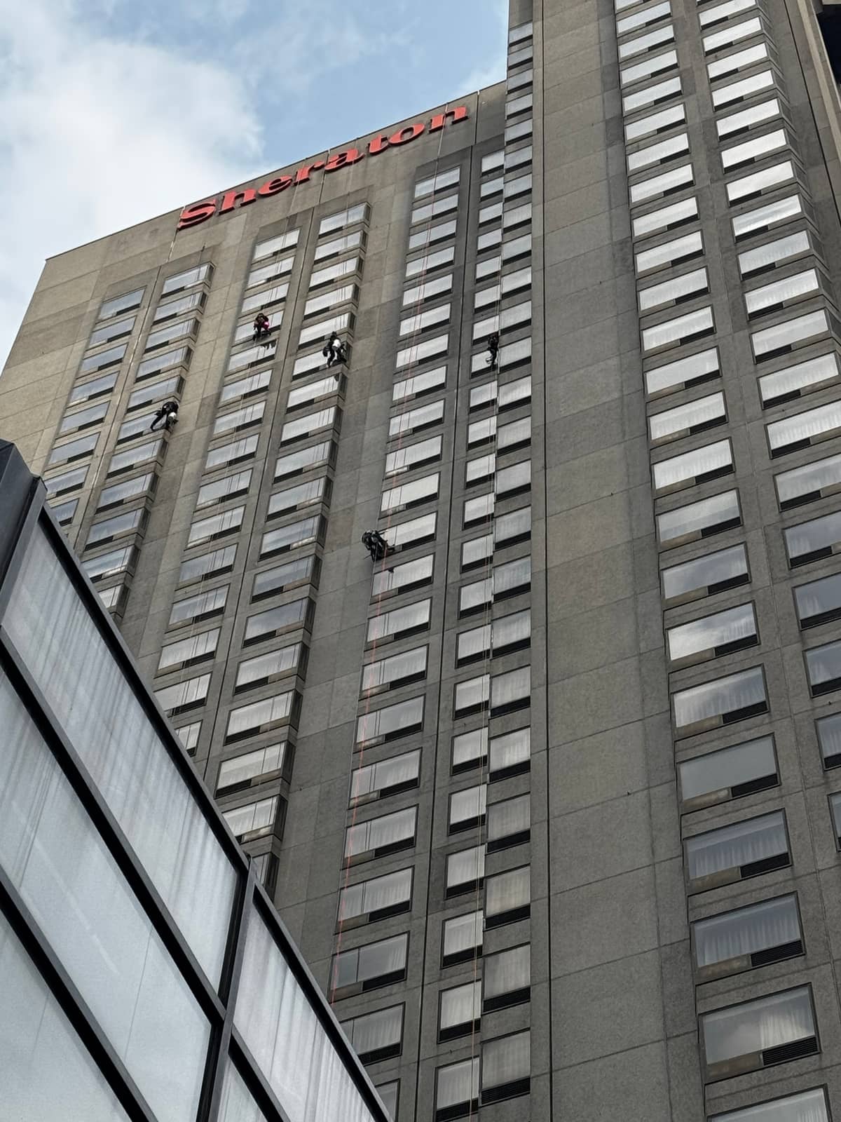 Rope access technicians cleaning the windows of a downtown tower