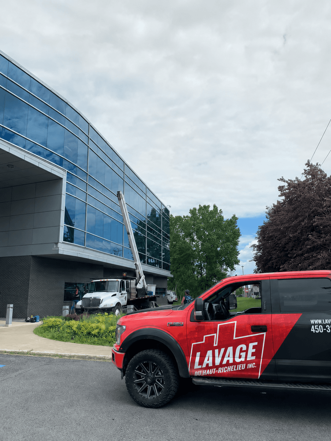 Lavage du Haut-Richelieu branded truck in front of an institutional building, boom lift at work