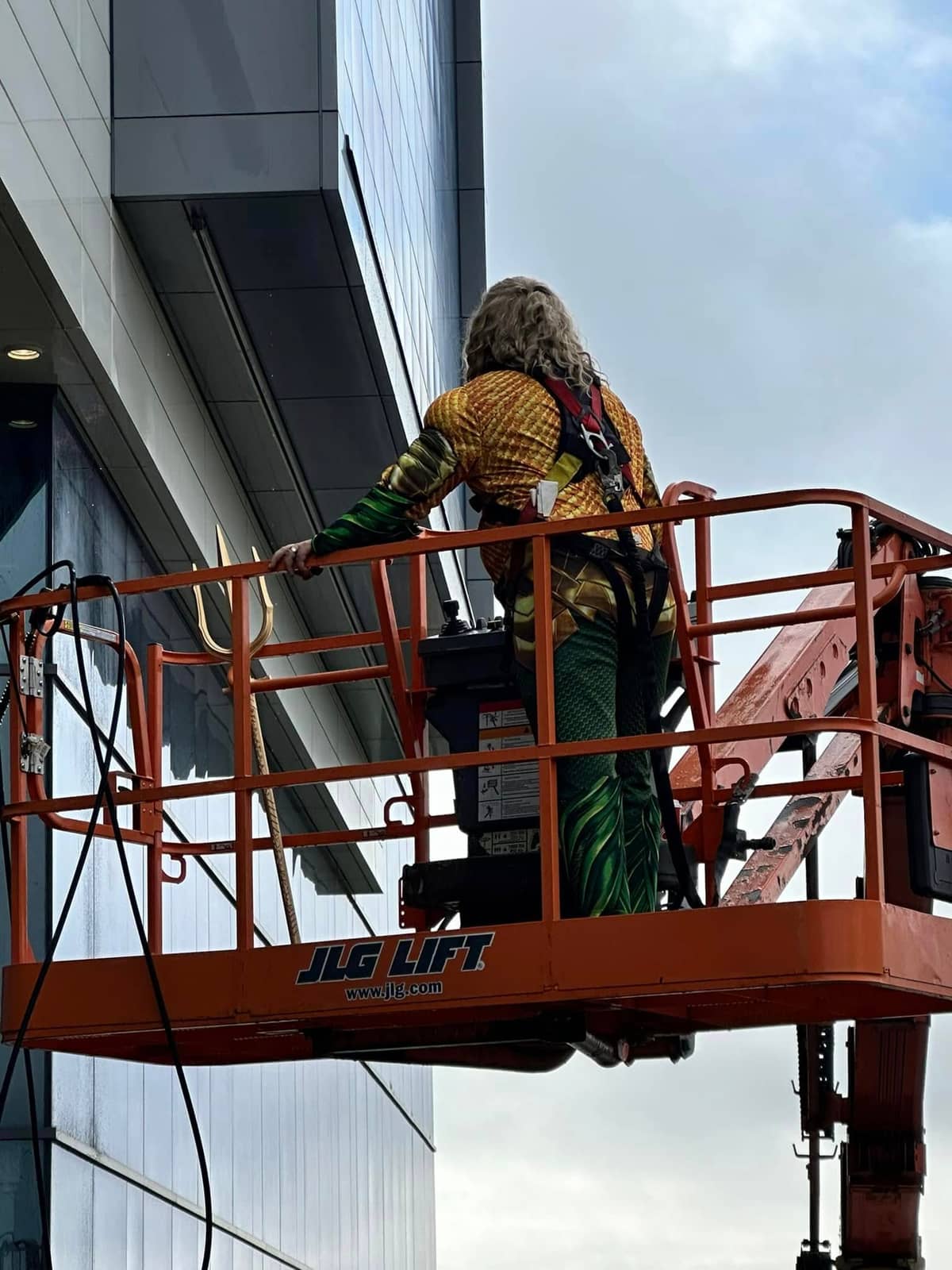Technician in an Aquaman costume cleaning a façade