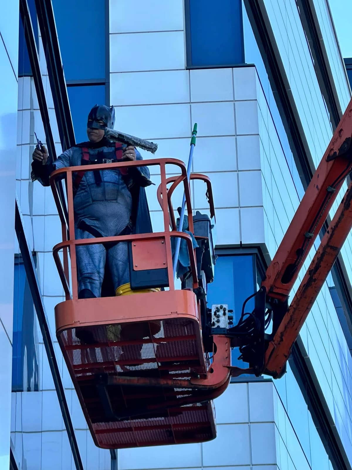 Technician in a Batman costume in a boom lift