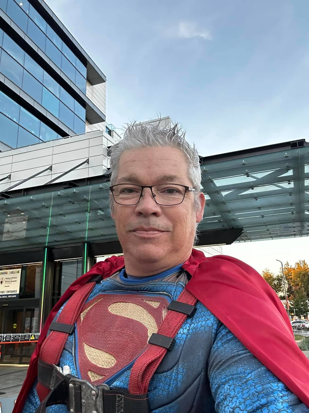 Technician in a Superman costume in front of Shriners Hospital